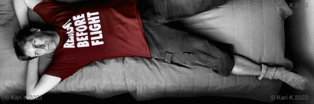 Valokuva henkilöstä makaamassa sängyssä selällään. Kuva otettu korkealta katonrajasta.